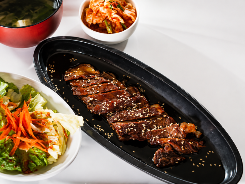 Beef Teriyaki with Real Japanese Sauce (15 Minutes) Shine-glazed beef, four-ingredient sauce, over hot rice. No garlic, no ginger — that's not teriyaki. Quick answer: Real Japanese teriyaki sauce is 4 ingredients only — soy sauce, sake, mirin, sugar, mixed 2:2:2:1. Simmer 8 minutes until it coats a spoon. Sear thinly sliced beef in a hot pan 60 seconds per side, add sliced onion and the sauce, glaze 90 seconds. Serve over rice with sesame and sliced scallion. Fifteen minutes start to bowl. No garlic, no ginger — that's the American takeout version. Prep5 min Cook10 min Total15 min Serves2 StyleJapanese (teriyaki-yaki) What Real Teriyaki Sauce Actually Is Teri (照り) means shine or glaze; yaki (焼き) means grill. Together: shine-grilled. The whole point is the glossy caramelized coating you get from reducing a specific 4-ingredient sauce over hot meat — nothing else. Real Japanese teriyaki has no garlic, no ginger, no honey, no cornstarch. As Namiko Chen at Just One Cookbook writes, "westernized versions are sweetened with honey and flavored with garlic and ginger" — that's a different sauce with the same name slapped on it. The 4 ingredients are soy sauce (salt + umami), sake (depth + tenderizer), mirin (sweetness + shine), sugar (extra body). Mix 2:2:2:1, simmer, done. The Ingredients (Beef + Real Sauce) For the sauce (makes ¾ cup, enough for 3–4 dinners) ¼ cup soy sauce — Japanese-style like Kikkoman, not Chinese light soy ¼ cup sake — Japanese rice wine, not cooking wine; dry sherry works if desperate ¼ cup mirin — sweet rice wine; the "hon-mirin" bottles are the real thing, "aji-mirin" is the mass-market fake 2 tbsp granulated sugar — regular white sugar; not honey, not brown For the beef teriyaki (serves 2) ¾ lb (12 oz) beef sirloin or ribeye, sliced ¼-inch thick across the grain — freezer-firm meat is easier to slice thin (see our how to slice beef thin guide) 1 yellow onion, halved and sliced ½-inch thick with the grain (they hold shape) 1 tbsp neutral oil — vegetable, avocado, or grapeseed. Not olive. 1 tsp toasted sesame seeds for finishing 2 scallions, thinly sliced on the bias Kosher salt, freshly ground pepper Serve over short-grain Japanese rice — walk through our how to cook Japanese rice guide if you've only ever done long-grain. How Do You Make Real Teriyaki Sauce? Combine the four ingredients in a small saucepan. Bring to a boil over medium heat, whisking until the sugar dissolves. Drop to medium-low and simmer 8–10 minutes until reduced by a third. You want it to coat the back of a spoon and hold a line when you drag your finger through — like maple syrup, not motor oil. The sake burns off alcohol in the first 2 minutes; the mirin caramelizes; the soy concentrates. When you smell that toasty-sweet aroma, kill the heat. It thickens more as it cools. Store the extra in a sealed jar in the fridge — it keeps 2–3 weeks and works on chicken, salmon, tofu, and grilled vegetables. How to Make Beef Teriyaki, Step by Step Make the sauce first. Whisk soy, sake, mirin, and sugar in a small saucepan. Simmer 8 minutes over medium-low until it coats a spoon. Set aside — it needs to cool slightly so it doesn't scorch when it hits the hot pan. Slice the beef thin. Firm the beef in the freezer for 15 minutes if it's not already cold. Slice across the grain into ¼-inch strips. Pat dry with paper towels — surface moisture equals steam, and steam is the enemy of the sear you need to build that glaze. Season and heat. Salt and pepper the beef right before it hits the pan (not earlier — salt draws out water). Heat 1 tbsp neutral oil in a heavy 12-inch skillet or wok over high heat until it shimmers and just starts to smoke. Sear the beef 60 seconds per side. Lay the slices in a single layer — don't crowd, work in two batches if you need to. Sear 60 seconds untouched, flip, another 60. You want browned edges, not gray. Transfer to a plate. Cook the onions. Same pan, no extra oil. Toss the sliced onion in the beef fond, cook 3 minutes over medium-high until edges are charred and centers still have crunch. Onions in real Japanese teriyaki are structure, not garnish. Return the beef and glaze. Slide the beef back into the pan with any juices from the plate. Pour ⅓ cup of the sauce over the top — the pan should sizzle hard. Toss constantly for 60–90 seconds until every piece is coated in glossy amber sauce. It should reduce and cling to the beef in the pan, not pool. If it pools, keep tossing. Plate over rice. Scoop hot rice into two bowls, mound the beef and onions on top, drizzle any remaining pan sauce, finish with sesame seeds and scallions. Eat while hot — the glaze goes tacky as it cools. Glaze clings, doesn't pool. If it's swimming, keep the heat on and toss. The Sauce Ratio Table (Scale as Needed) BatchSoySakeMirinSugarSimmer Single dinner (2 people)¼ cup¼ cup¼ cup2 tbsp8 min Family (4 people)½ cup½ cup½ cup¼ cup12 min Big batch (jar for the fridge)1 cup1 cup1 cup½ cup15 min Sweeter (western palate)samesamesame+1 tbsp per ¼ cup soysame Keep the ratio as 2 : 2 : 2 : 1 (soy : sake : mirin : sugar). Every mL you shift makes a noticeable difference. This is the ratio chef Marc Matsumoto documents at No Recipes as the classic Japanese proportions — the same one taught in professional Japanese kitchens. Watch the Method (2 Minutes) The Three Mistakes That Kill the Glaze 1. Adding garlic and ginger. American takeout swaps in garlic and ginger because it makes cheap beef taste like something. Real teriyaki relies on the sake-mirin-soy backbone alone — those aromatics muddy the shine. If you want stir-fry, make stir-fry. 2. Using cornstarch to thicken. Chinese-American teriyaki sauce uses cornstarch slurry, which is why it goes gloopy and gray. Real Japanese teriyaki thickens from sugar caramelization and soy reduction alone. Give it the full 8 minutes of simmer. 3. Adding sauce too early. Pour teriyaki sauce onto raw beef and the sugar burns before the meat cooks through. Sear the beef first, add sauce only in the last 90 seconds. The sauce is finishing, not marinating. What About Marinating? Skip it. Traditional Japanese beef teriyaki is not marinated — the technique is called yaki, which is a fast, high-heat sear. Marinating thin slices makes them steam instead of sear, and you lose that crisp glaze. Save marinating for the western fusion version with chicken thighs and honey. If you want a stronger flavor imprint, brush the seared beef with sauce and torch it for 10 seconds, or throw the pan under a broiler for 30 seconds after glazing. The controlled caramelization is what "shine-grilled" actually means. Broccoli is a Western addition — the classic Japanese plate is beef, onion, rice. Both work. What to Serve With Beef Teriyaki The traditional plate: short-grain rice, a small pile of quick-pickled cucumber (sunomono), a bowl of miso soup, and shredded green cabbage on the side. Total meal in under 20 minutes if the rice is going in parallel. For a bigger spread, add gyoza dumplings, a bowl of edamame, or our quick pickled cucumber recipe that finishes in 10 minutes. Cold Sapporo or a dry sake pairs; a light Riesling works if you're anti-beer. For similar 15-minute dinners built on the same speed-cooking logic, our Asian recipes collection is the next stop. Common Questions Can I use mirin substitute? Yes, but it changes the sauce. Standard sub: 1 tbsp dry sake + 1 tsp sugar per 1 tbsp mirin. Sweet white wine works in a pinch. What you can't sub for is the shine — mirin has a specific low-alcohol high-sugar profile that produces that unique glaze. Real mirin gives real teriyaki. What's the best beef cut for teriyaki? Ribeye is the best for flavor; sirloin is the best value. Both slice thin without going stringy. Avoid tenderloin (too lean, no fat to render), skirt steak (too fibrous unless perfectly cut), and pre-sliced "stir-fry meat" from the freezer aisle (usually low grade with excess connective tissue). Can I make teriyaki sauce without sake? You can, but call it something else. Sake carries specific umami compounds — glutamates and amino acids — that soy and mirin alone don't provide. If you must, substitute dry sherry or Chinese Shaoxing wine. Skip the alcohol entirely and you get a flat, one-dimensional sweet-salty glaze. How long does homemade teriyaki sauce keep? 2 to 3 weeks in the fridge in a sealed jar. The high sugar and salt content preserves it. It's also freezer-friendly — pour into ice cube trays, freeze, and pop out cubes as needed. One cube (2 tbsp) glazes one portion of beef, chicken, or salmon. Can I use this sauce on other proteins? Yes — that's the whole point of making a batch. Salmon teriyaki is the second-most-common dish in Japan (probably first, actually). Chicken thigh yakitori, tofu steaks, grilled shrimp, even glazed vegetables all use the same 4-ingredient reduction. See our Japanese pantry basics guide for the ingredients that unlock the whole cuisine. The Short Version Simmer soy + sake + mirin + sugar (2:2:2:1) for 8 minutes. Sear thin-sliced beef 60 seconds per side in a hot oiled pan. Add onions, cook 3 minutes. Return beef, add sauce, toss 90 seconds until glaze clings. Plate over hot short-grain rice, top with sesame and scallions. Real Japanese teriyaki, 15 minutes, four ingredients that matter. For more single-pan weeknight dinners on the same 15-minute timeline, browse our quick dinners collection — same discipline, different plate.