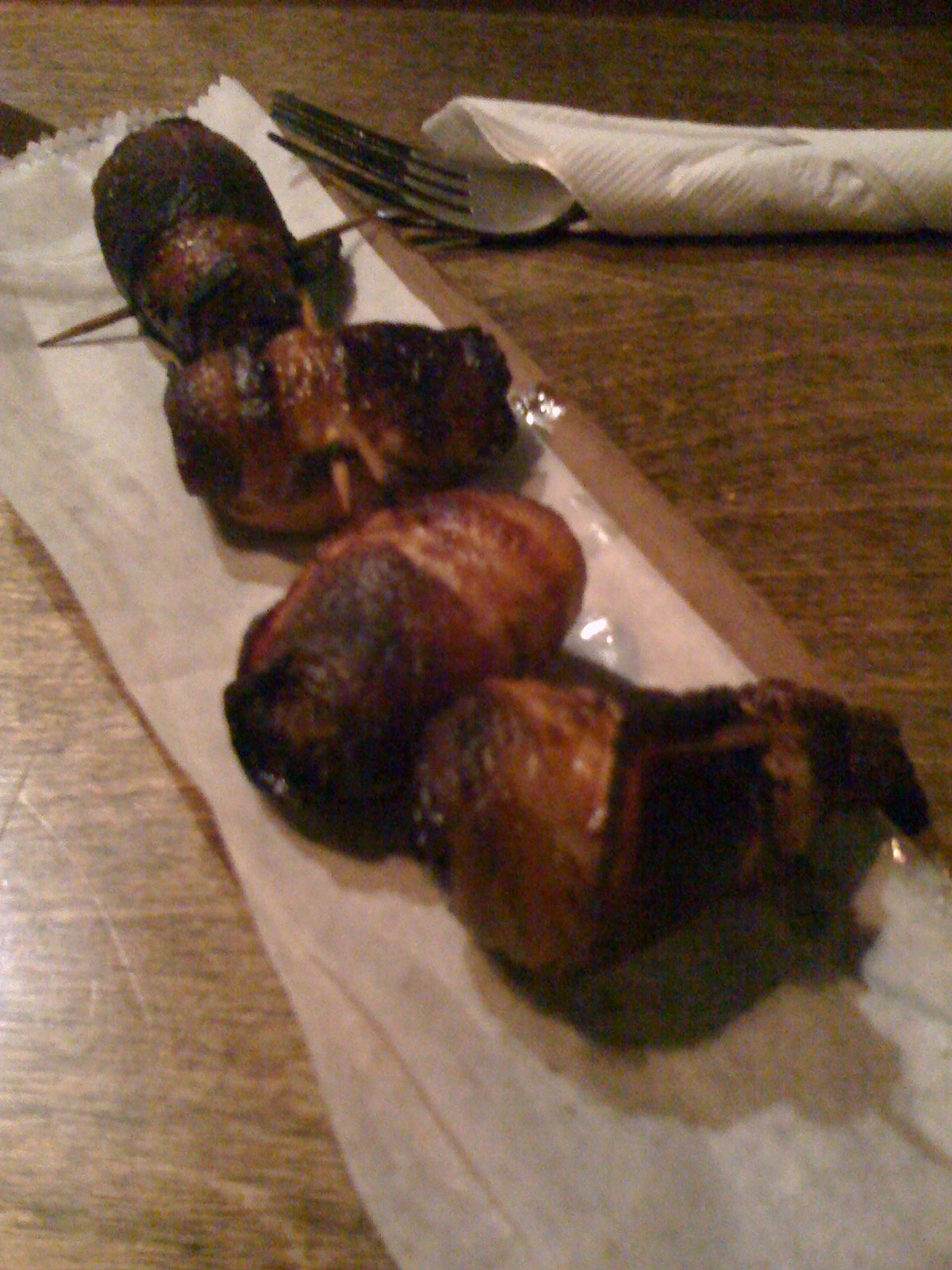 Bacon-wrapped almond-stuffed dates on toothpicks served on parchment