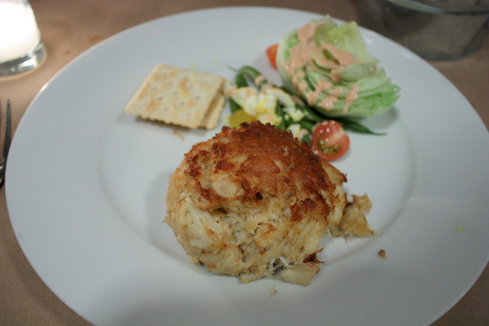 Baltimore restaurant crab cake on a white plate with saltine crackers and a side salad