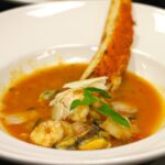 Bowl of tomato seafood stew with shrimp and mussels and a toasted bread crouton