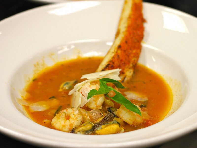 Bowl of tomato seafood stew with shrimp and mussels and a toasted bread crouton