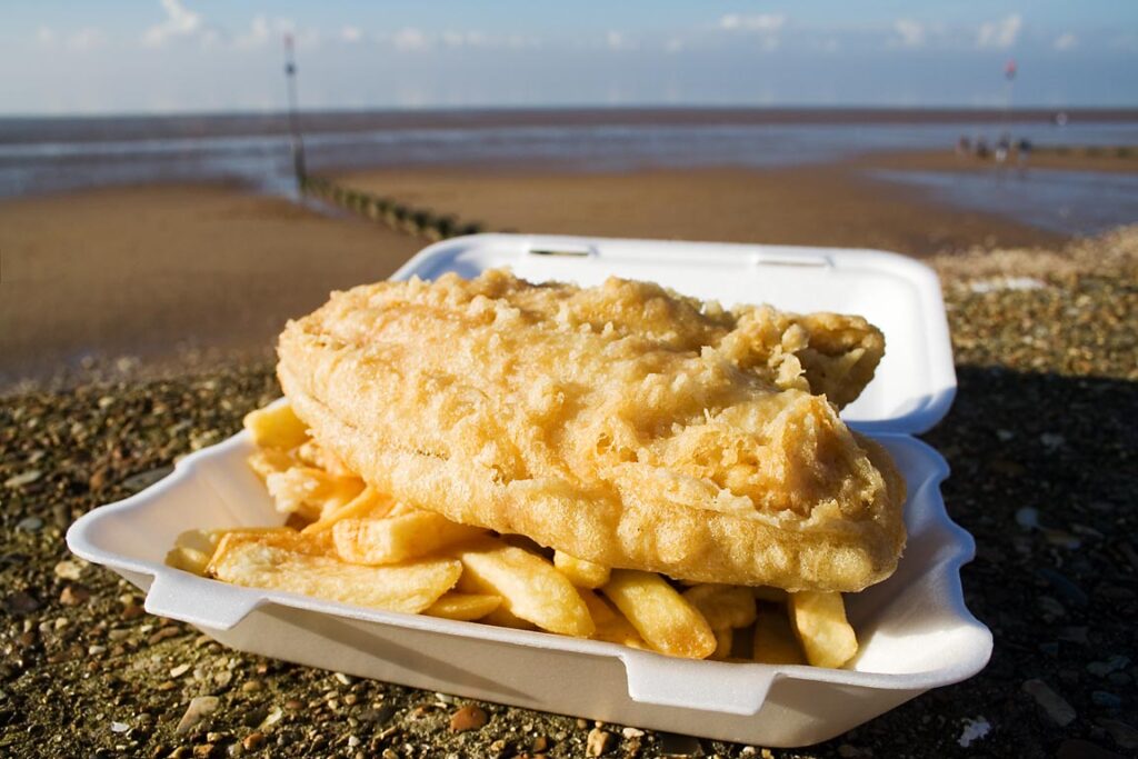 Takeaway fish and chips in a polystyrene tray on the seafront at Hunstanton