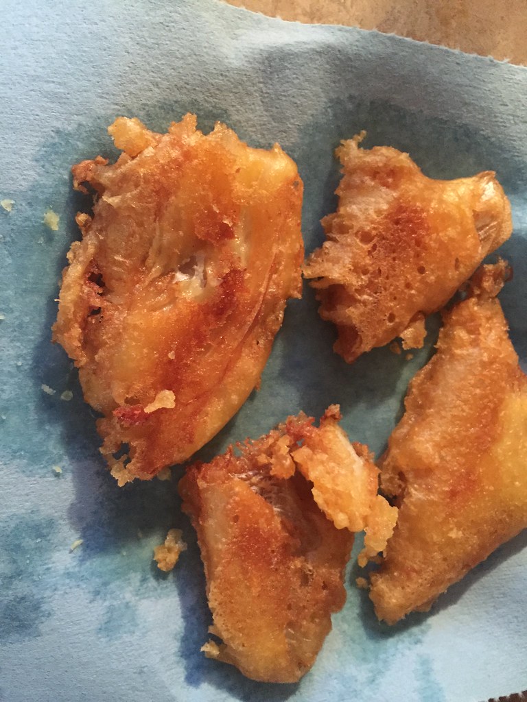 Home-fried battered cod pieces with a puffy golden crust draining on paper