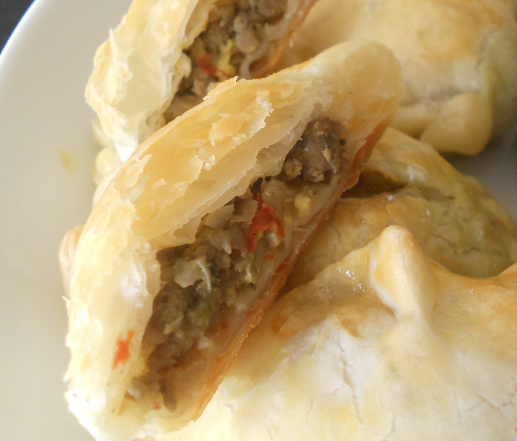 Flaky baked beef empanada cut open to show the spiced ground beef filling