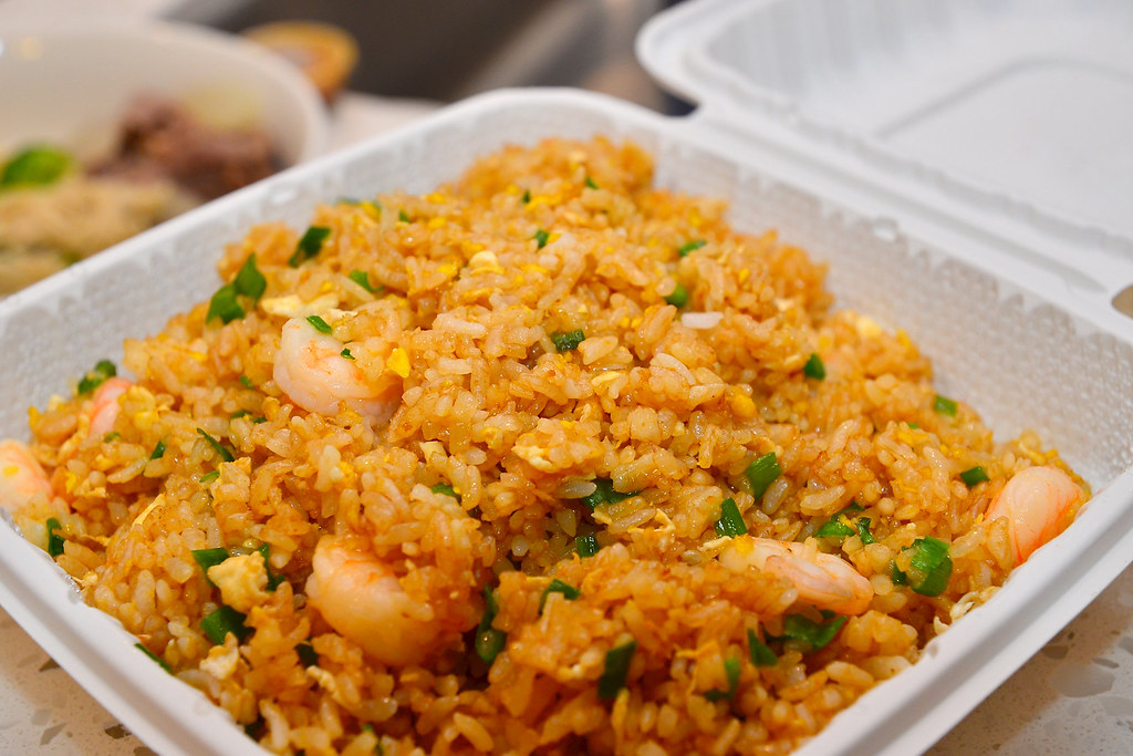 Restaurant shrimp fried rice with egg and scallions in a takeout container