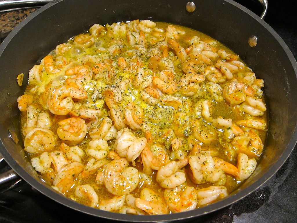 Large batch of shrimp scampi in garlic butter sauce in a nonstick skillet on the stove